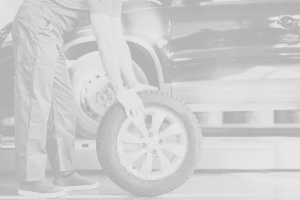 Mechanic holding tire by car